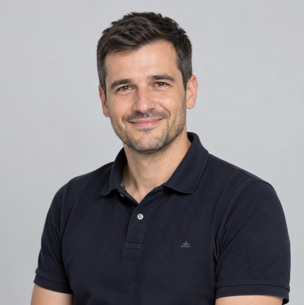 Studio portrait of a smiling man in a dark polo shirt